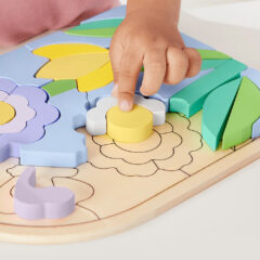 Niño armando el rompecabezas de flor de madera Fisher-Price por su cuenta