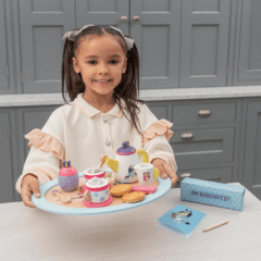 Una niña juega con el set de té de madera en la cocina.